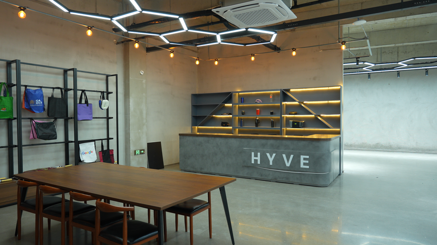 Modern office space with 'HYVE' branding, desks, and shelves.